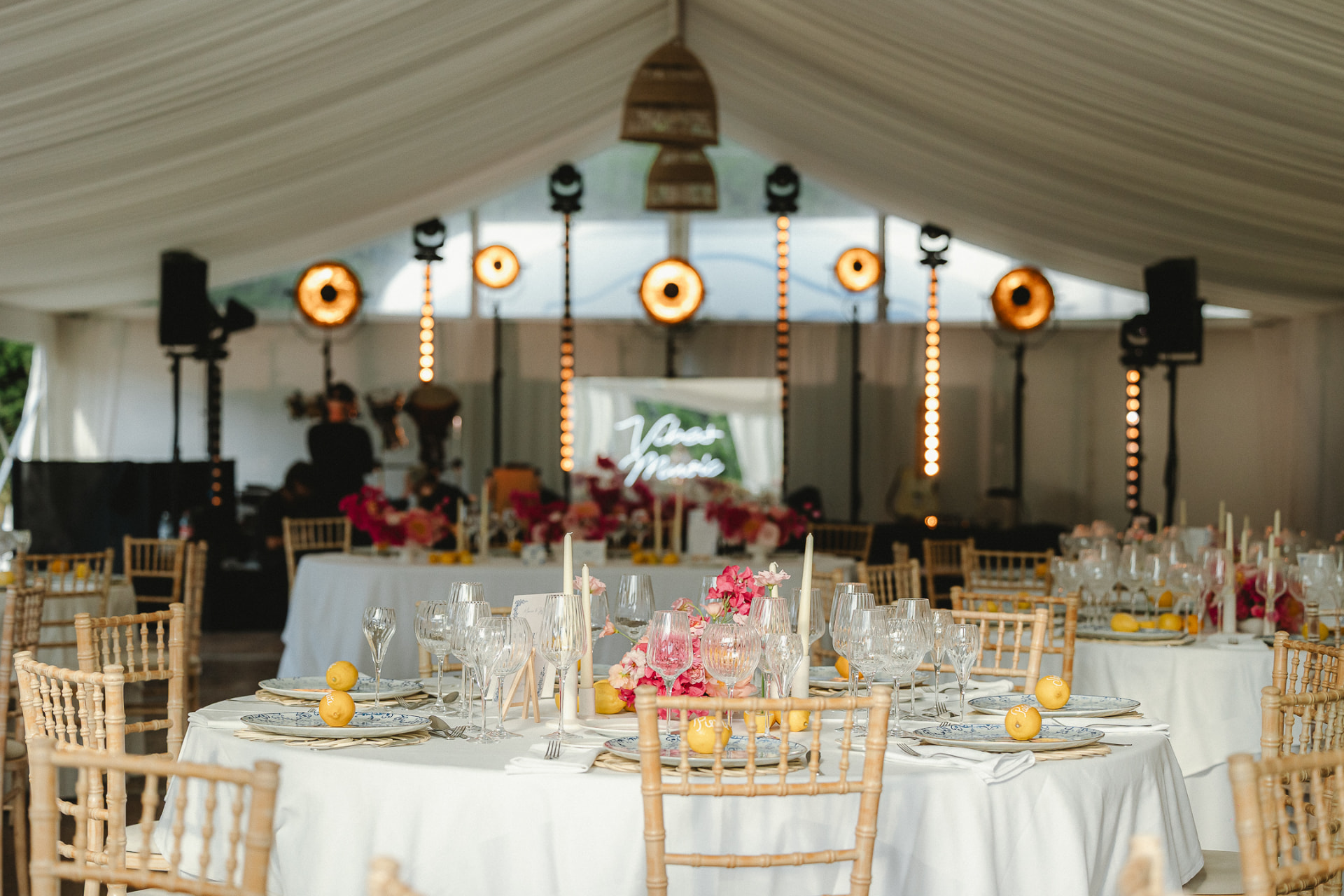Salle de réception sous tente blanche, tables dressées et scène lumineuse au Mas Baïeta