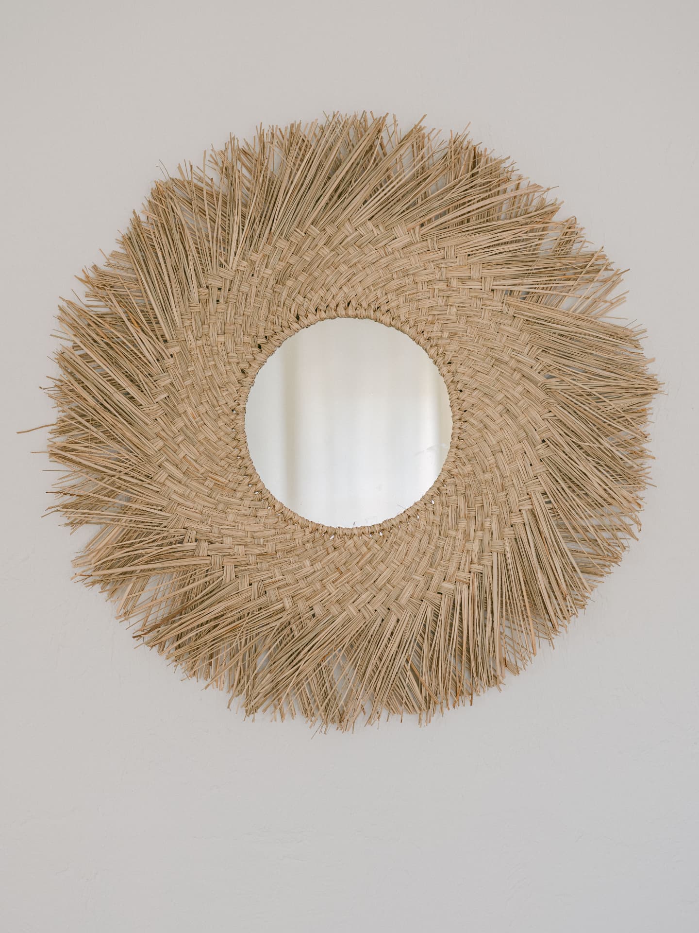 Miroir circulaire encadré de fibres naturelles tressées en soleil